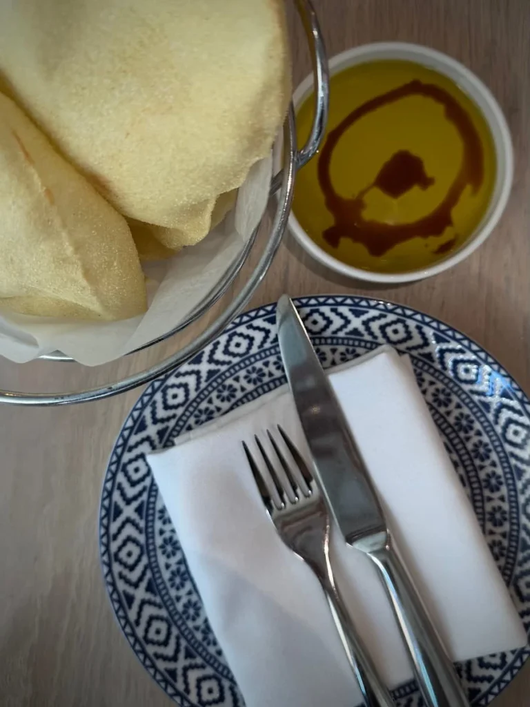 Top lay of flat breads, olive oil, balsamic vinegar and cutlery with napkin at Zaytinya, Washington DC on a white table top