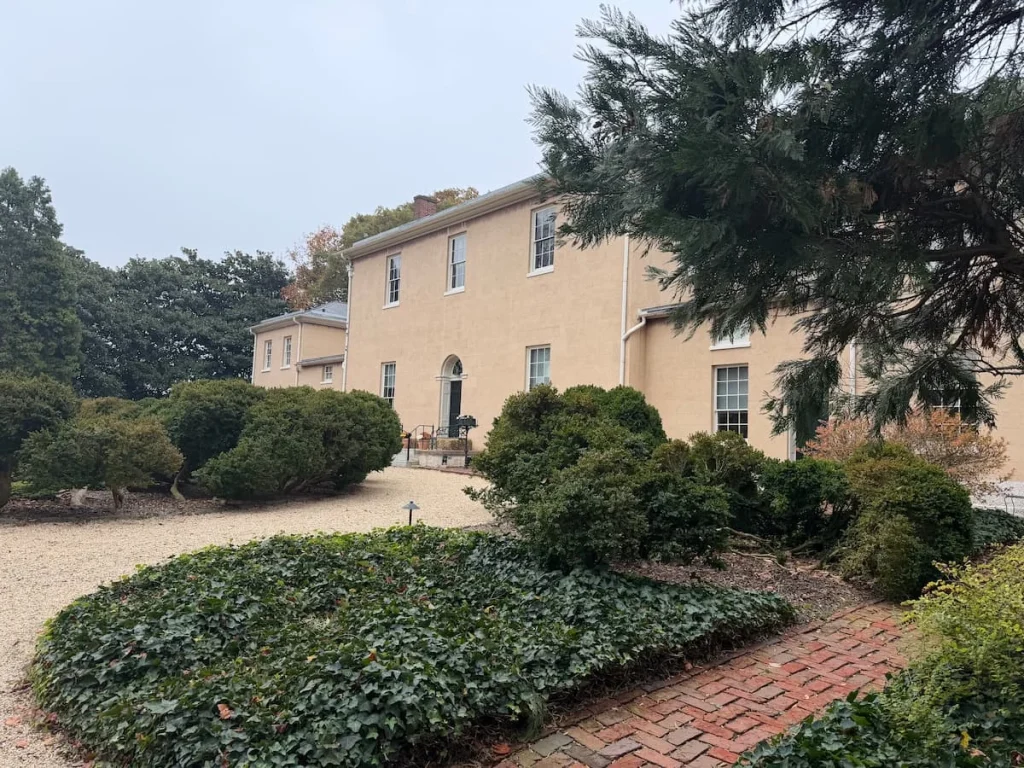 Tudor House, Georgetown Washington DC with its cream fascia and trees, foliage and flowers covering the front of the house