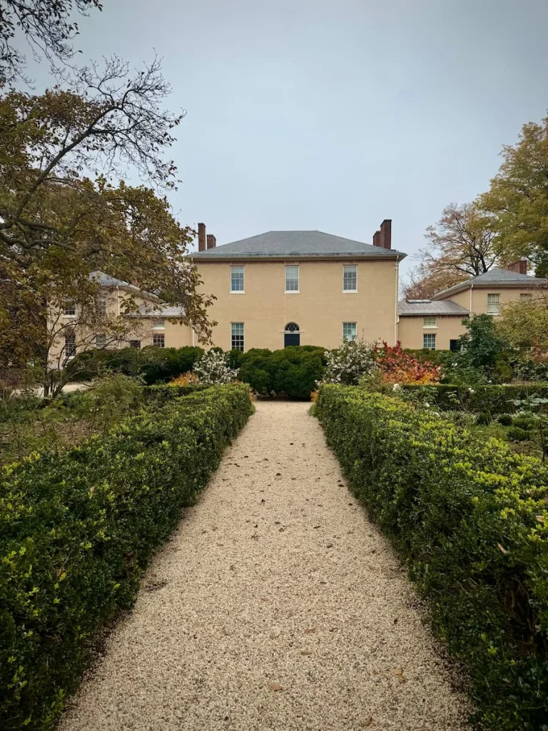 Tudor Place with a hideg and walkway in the centre gravelled in Georgetown Washington DC. The gravel path leads to the cream fronted Tudor style house