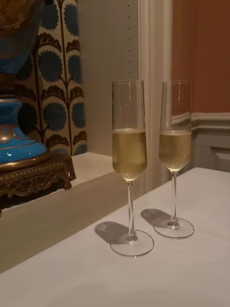 Two glasses of sparkling wine at Elizabeths, Washington DC on a white tablecloth next to an alcove with a blue and bronze vase