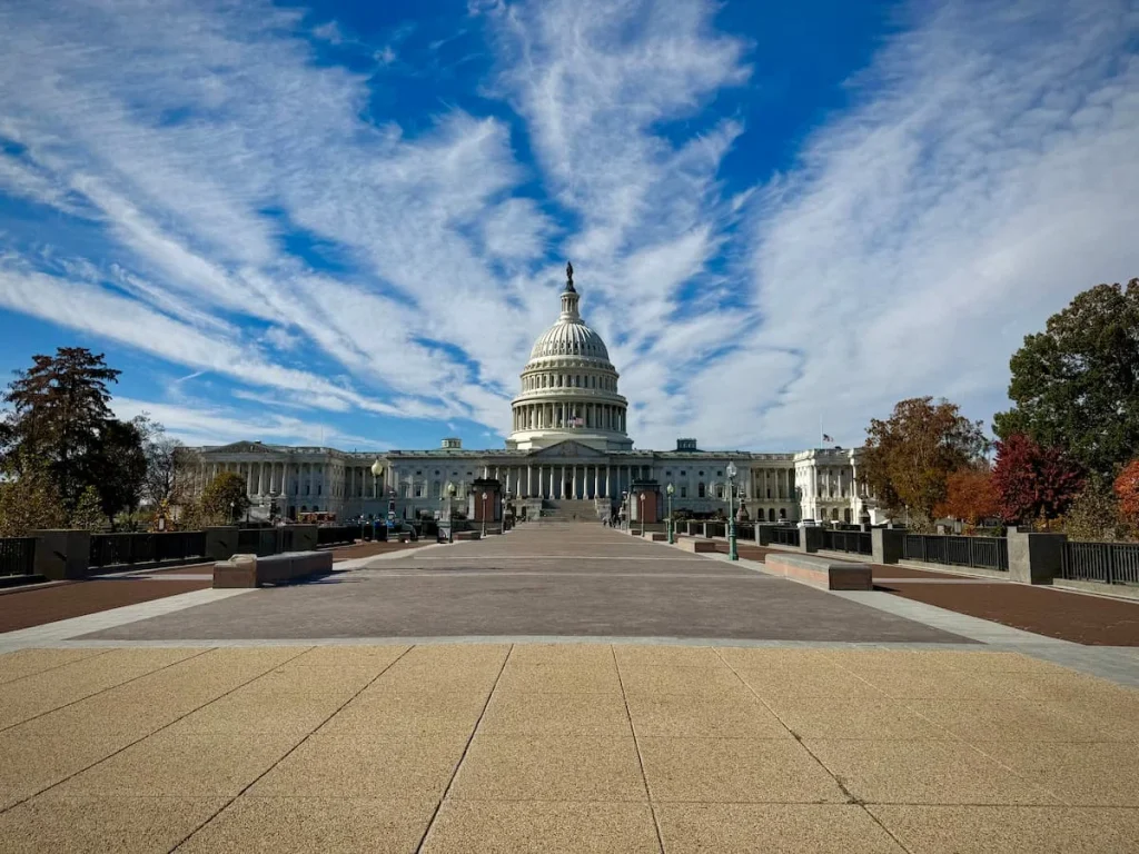 US Capitol Building from a distance, Washington DC with blue skies adn clouds in the background. One of the Washington DC neighbourhoods for first-time visitors