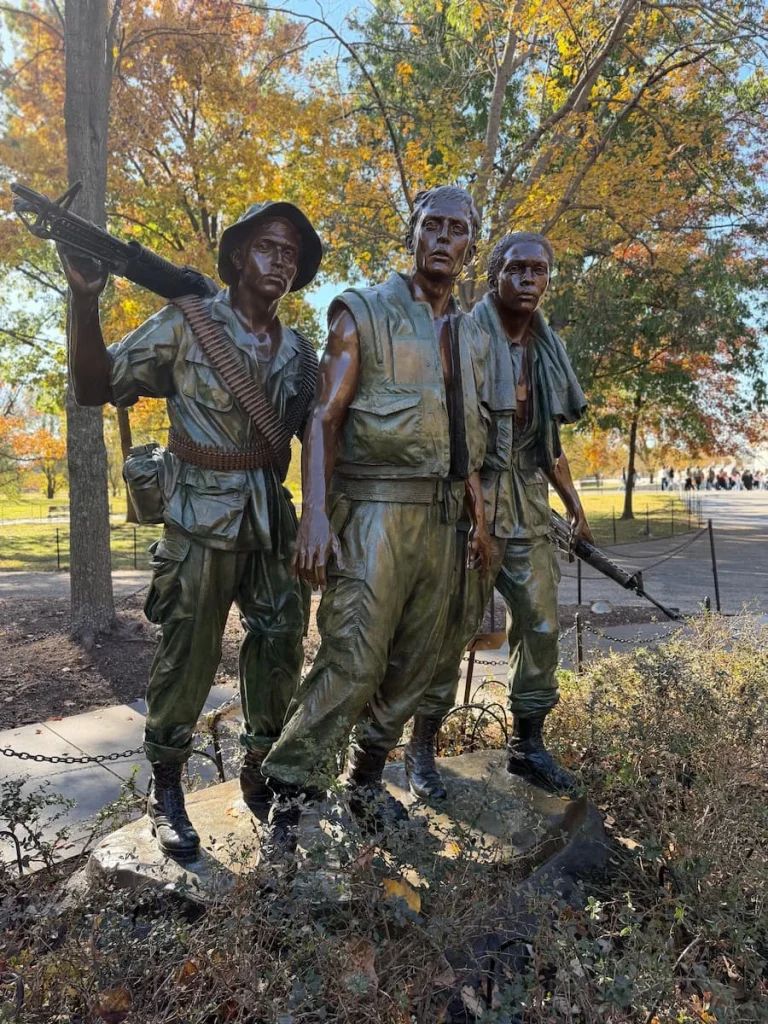 Vietnam War Memorial Washington DC statues, 3 of them standing with guns on a small podium