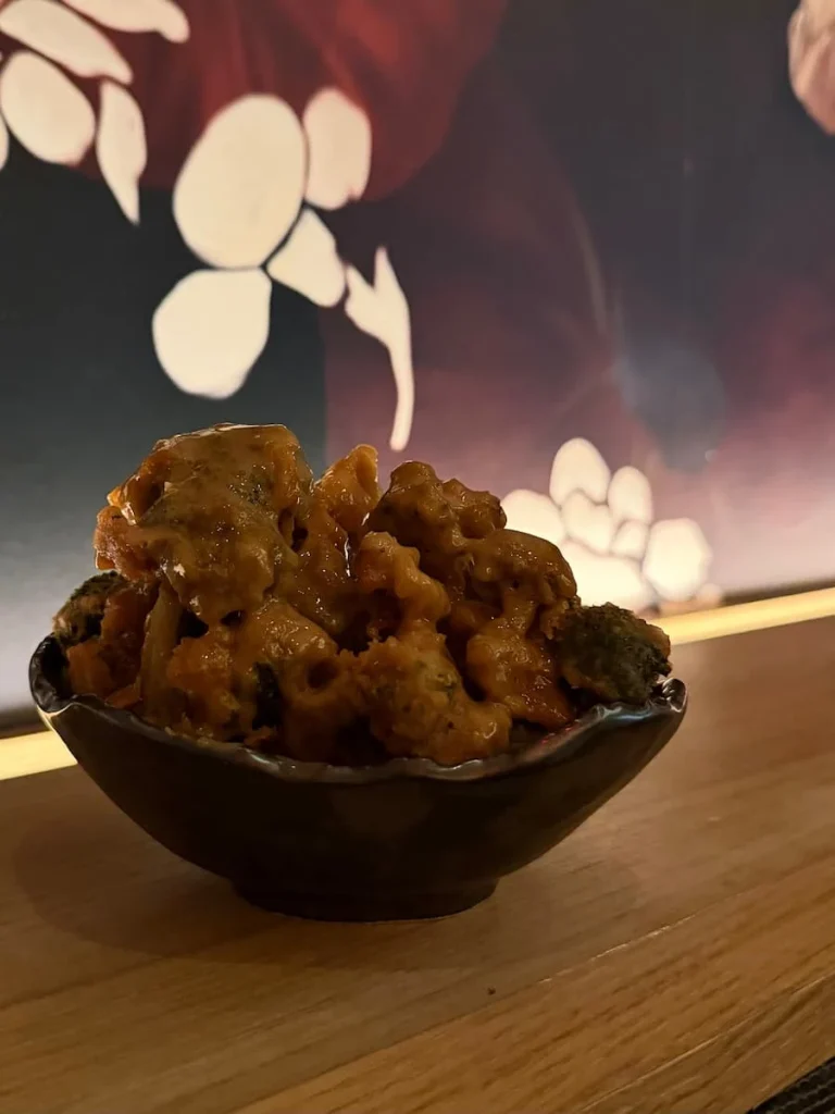 crispy broccoli tempura bowl at Planta, Washington DC. The black bowl is on a oak wood counter with the signature Planta pink dragon wallpaper