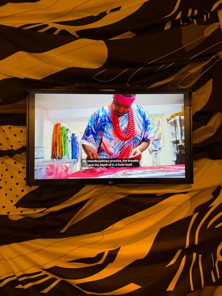 Film about African American artist on a TV screen on a wall towards the back of the hotel