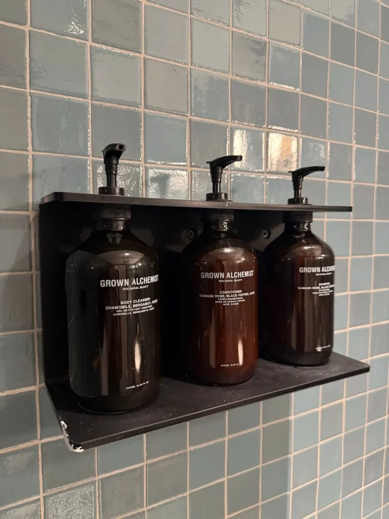 Full size bathroom products at Eaton DC, Washington DC in dark brown dispenser containers inside the shower compartment