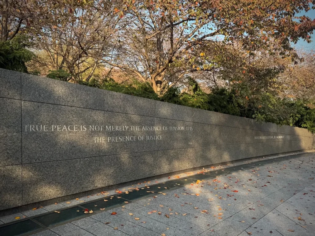 Martin Luther King Quote in Washington DC engraved on a marble wall with autumnal trees in the background