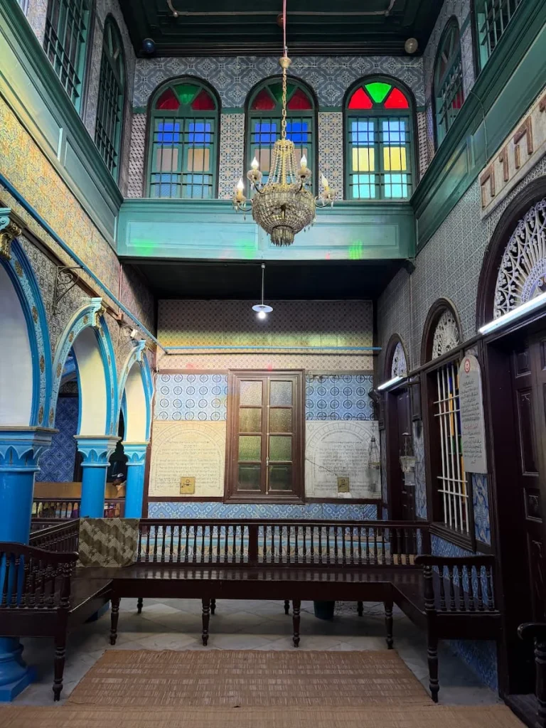 Alter at El Ghriba Synagogue, Djerba, with a chandelier hanging down and stained glass windows at the top