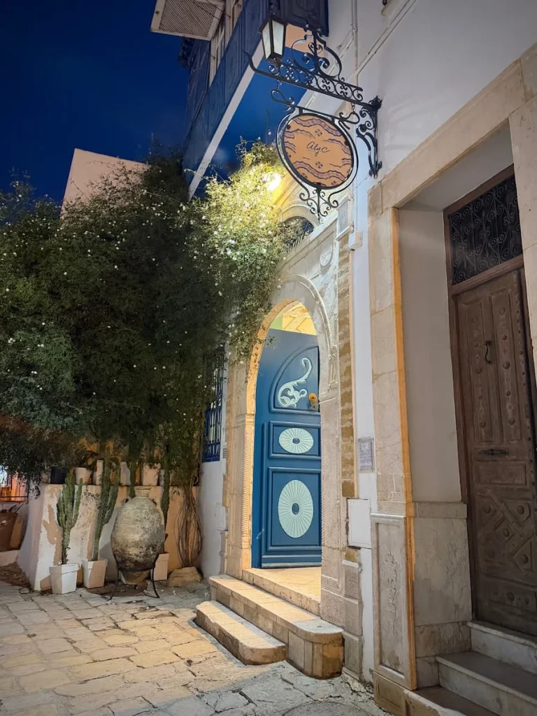 Aly C Gallery, blue front door with a sign and foliage around it in Sidi Bou Said, Tunisia
