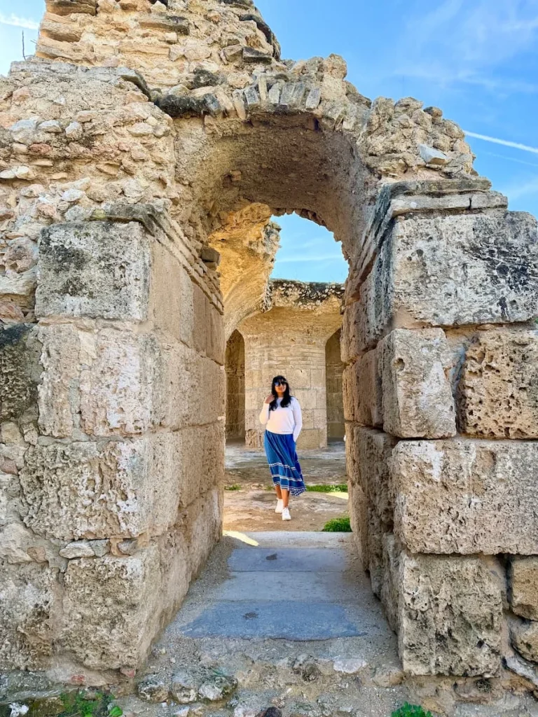 Antoninian Baths, Carthage, stone archways.Tunisia. Bejal is standing in the archway wearing a white top and blue skirt.