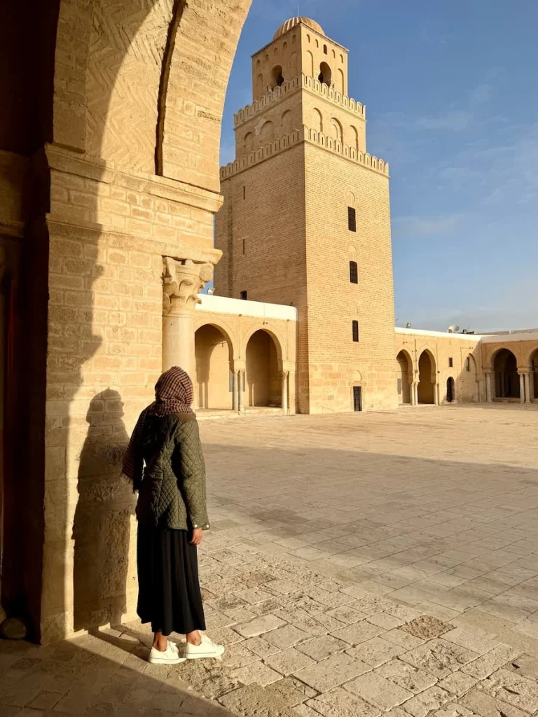 Bejal in courtyard of Mosque of Okba, Kairouan, Tunisia. bejal is looking at the minuret and her head is covered with a scarf