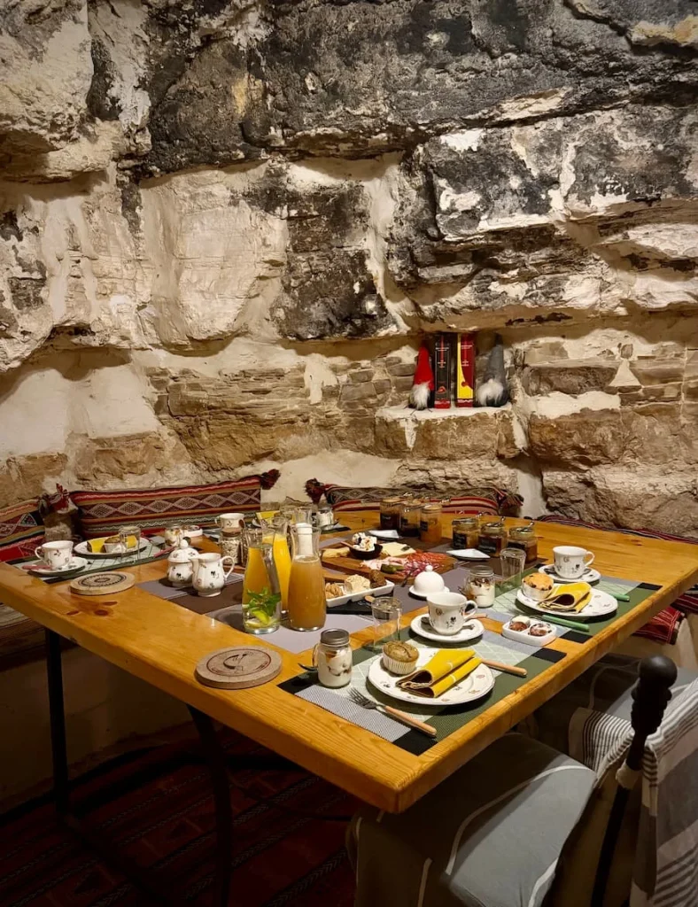 Wooden square breakfast table at L'Auberge de Tamezret. There is oranje juice, coffee, bread, preserves and more laid out on the table