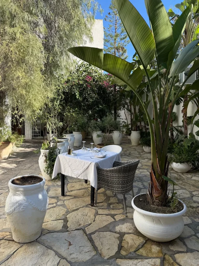 Courtyard at Chez Achour, Hammamet with a table in the centre with a white table cloth and dressed fro lunch. The surrounding courtyard has potted plants and trees