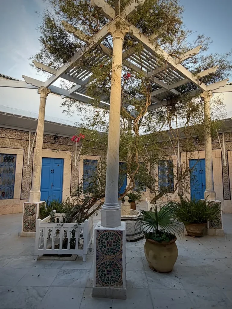 The Courtyard of Dar Said in Sidi Bou Said. The centre is open to the air and has draping plants coming down. There are a number of blue doors around teh courtyard which are guest rooms