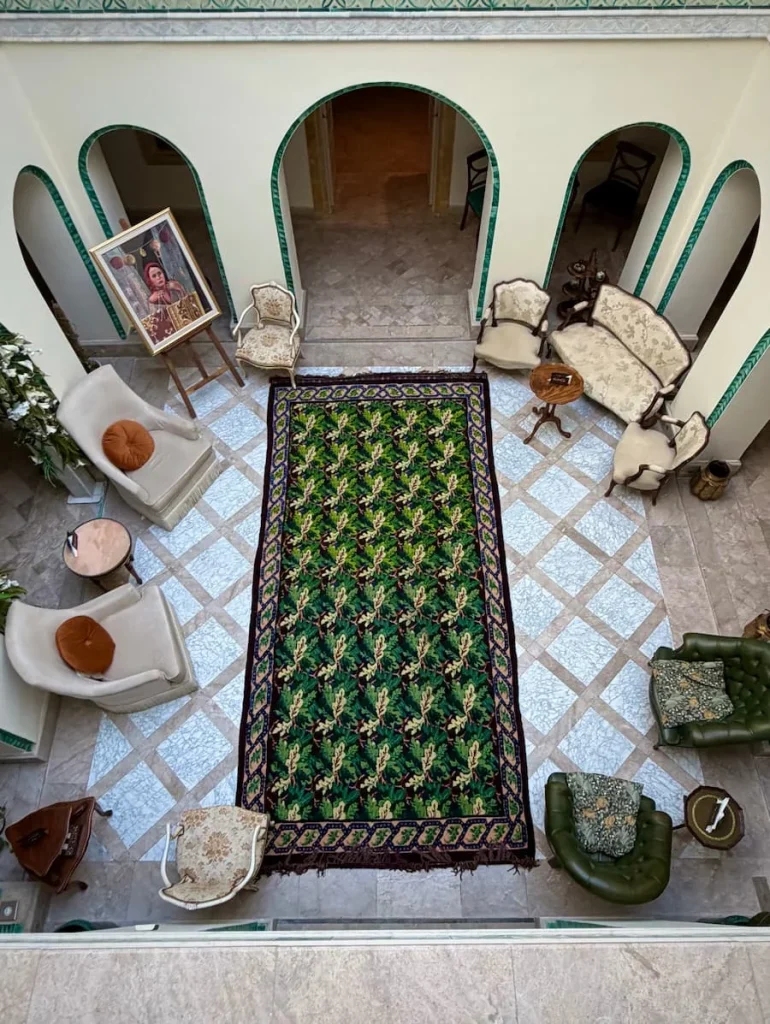 Dar Alouini ground floor courtyard in Kairouan, Tunisia.the floor is green and white checked tiles with white tile surround with seating at each of the cotners.