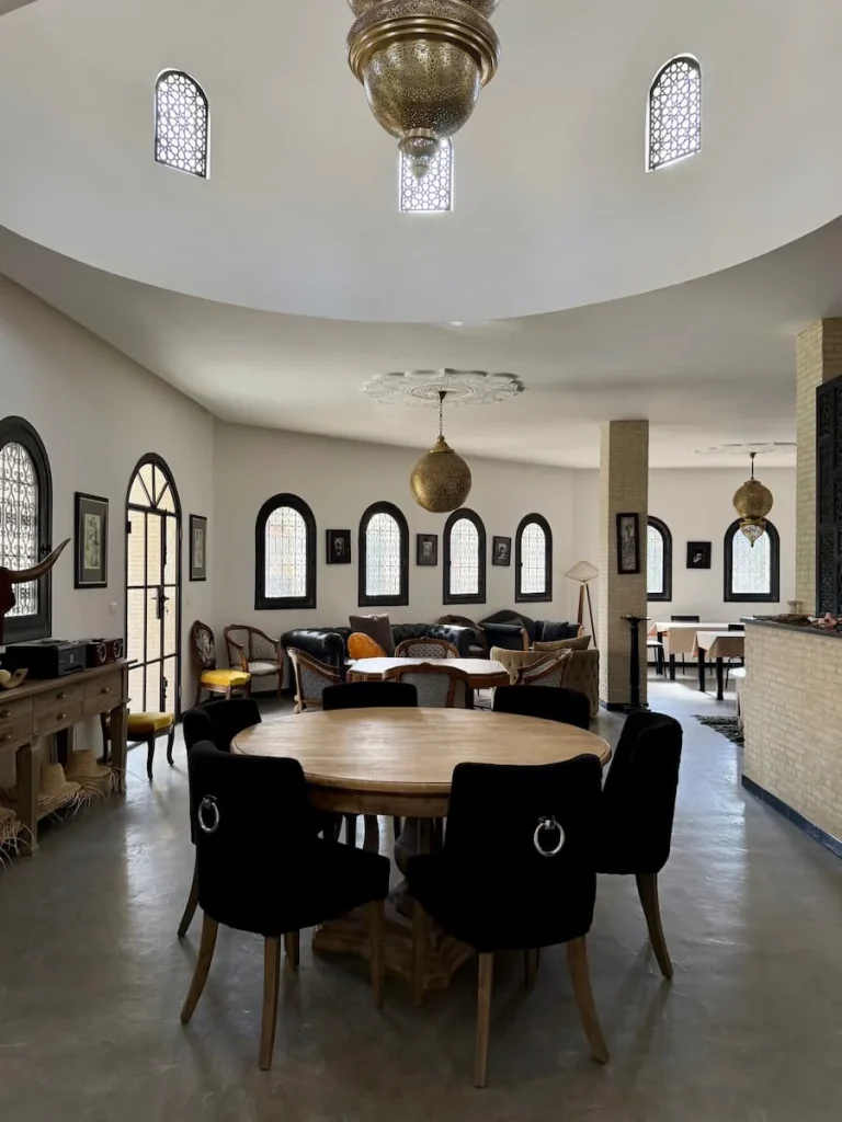 The interior traditional Tunisian style dining room decor at Dar Yomma, Tozeur. Theer's a round table in the middle with antique style hanging lights from the ceiling