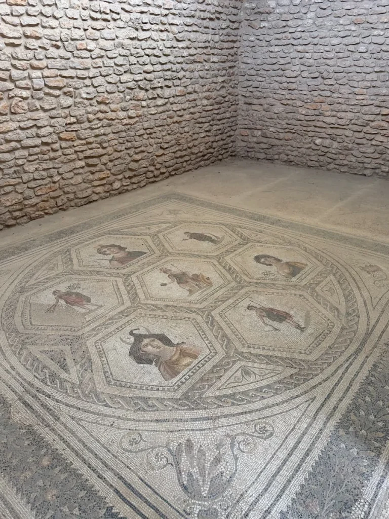 El Djem Archaeological Museum inside a room with Roman mosaics on the floor in varying shades of grey and brown