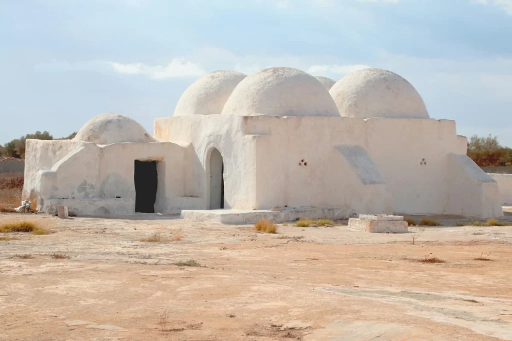 The white-washed domes of the Fadloun Mosque in Djerba with the sandy floor and blue skies