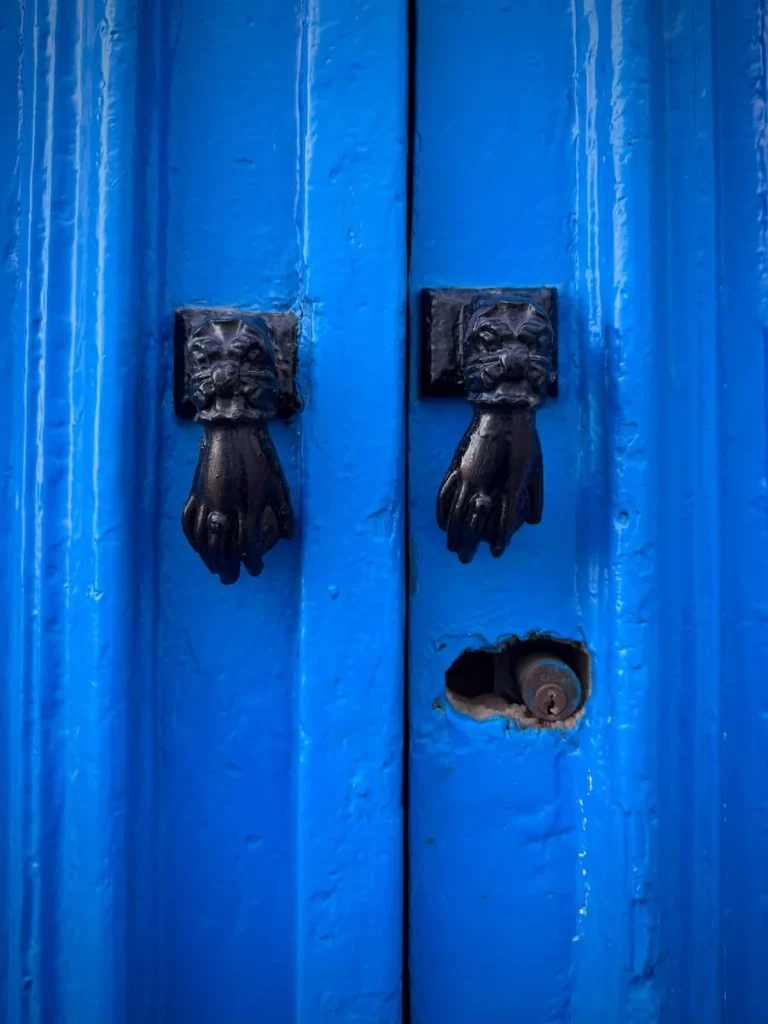 Black hands of Fatma door knockers on a bright blue door in Sidi Bou Said