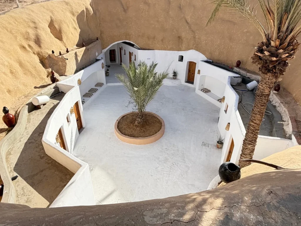 Aerial view of Hotel Driss in Matmata with teh traditional Berber style white, a central courtyard and palm tree in the centre, located in Matmata