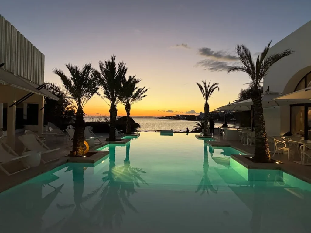 Infinity pool at La Badira in Hammamet during sunset. There are palm trees at either side of the infinity pool