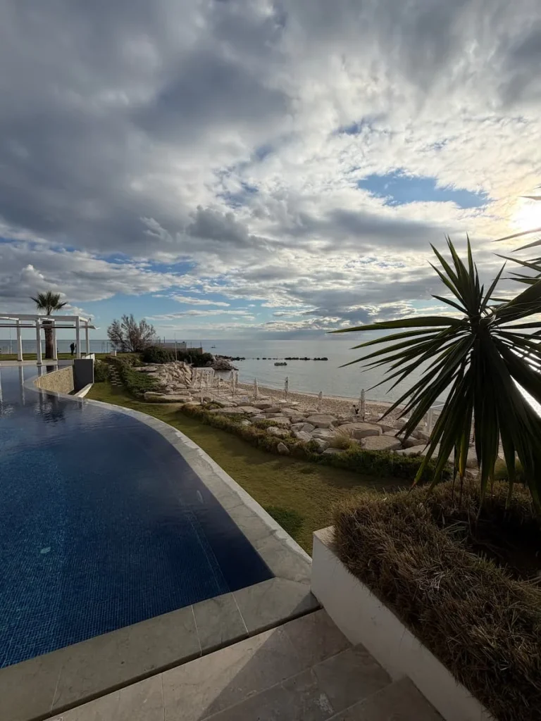 La Badira Beach, Hammamet. The infinity pool is to the left and the beach is to the right with palm trees swaying as the sky is a little overcast
