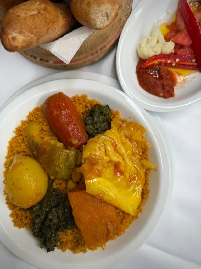 Couscous with vegetables in a tomato sauce adn bread on the side as well as peppers at Fondouk el Attarine