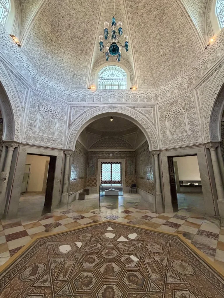 Mosaic room at Bardo Museum, Tunisia. The mosaics are all over the ceiling sides and walls with a large chandelier at the top of the tiled ceiling.