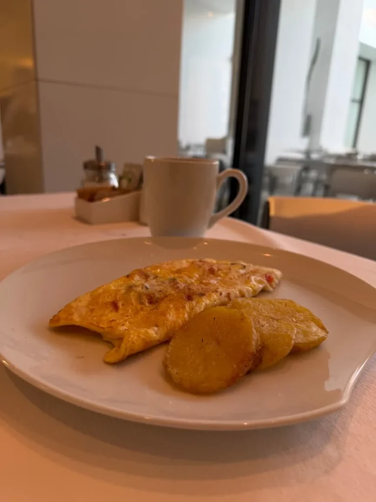 Breakfast plate at La Badira in Hammamet. The white plate has an omelette and potato slices plus a cup of a coffee