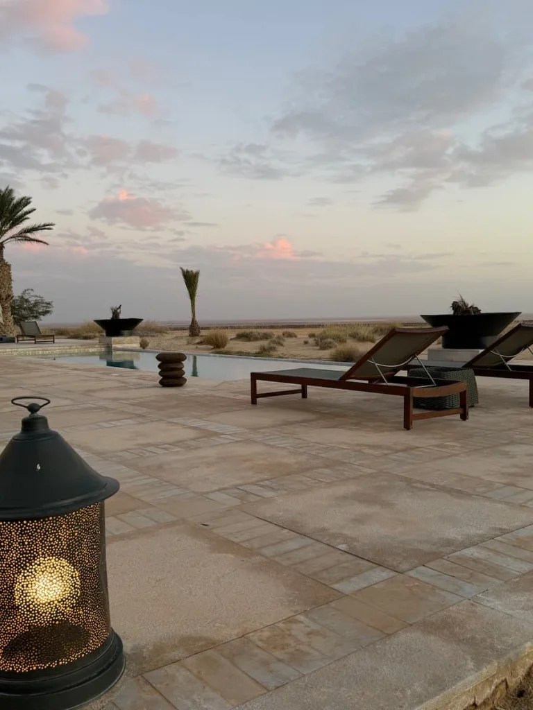 Plunge pool and loungers outside villa at The Mora, Tozeur. The sun is about to set in the distance and there are lanterns near the pool
