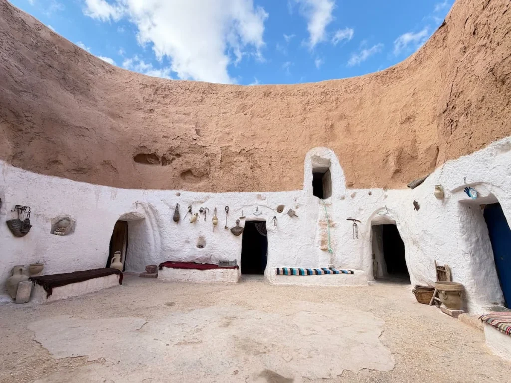 Real Troglodyte House, in Matmata Tunisia. The top has the sandy clay look with a white lower layer with windows and doors
