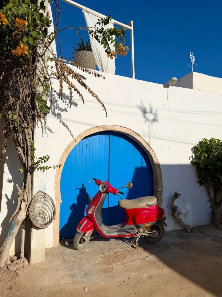 Red Scooter in Dejerba infront of a bright blue semi-crrclar door entrance