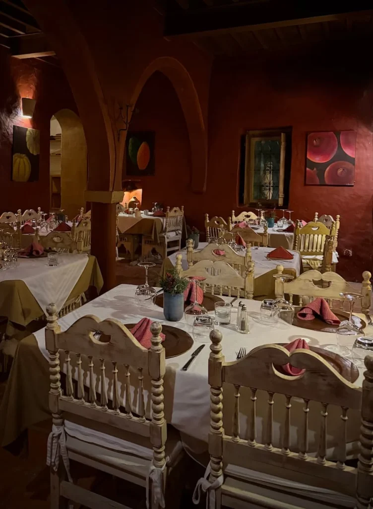 Restaurant at Dar Dhiafa, Djerba with its' maroon walls and traditional style seating and tables set with white table cloths