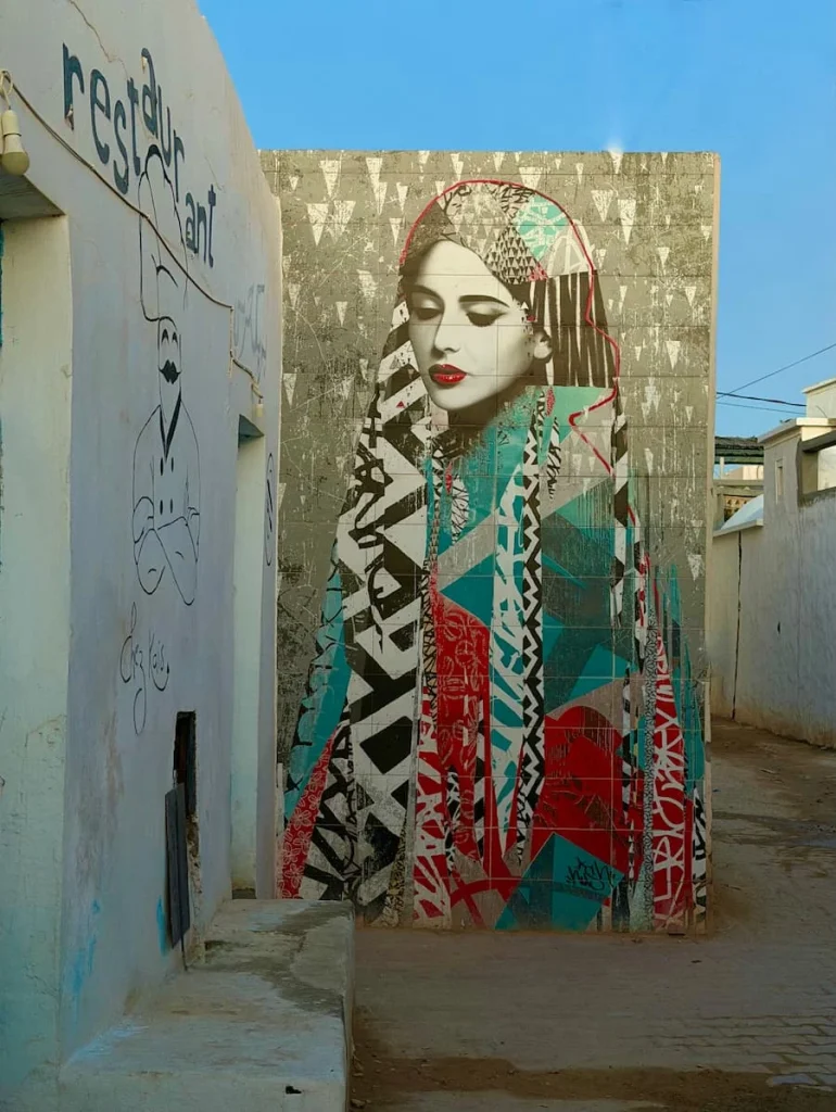 Street art of girl in Erriadh, Djerba. The girls has a multicolour dress on and yellow hair
