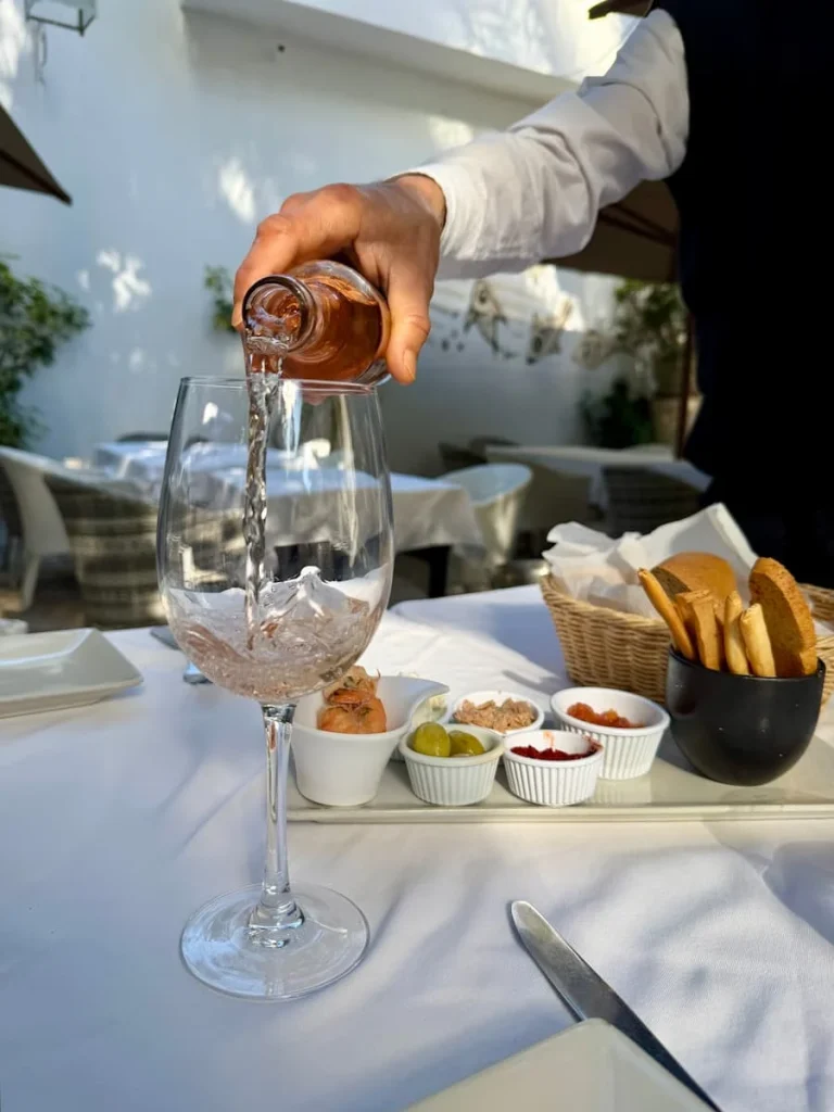 Tunisian Wine at Chez Achour being poured, Hammamet. The starters of bread, peppers and olives are in the background.