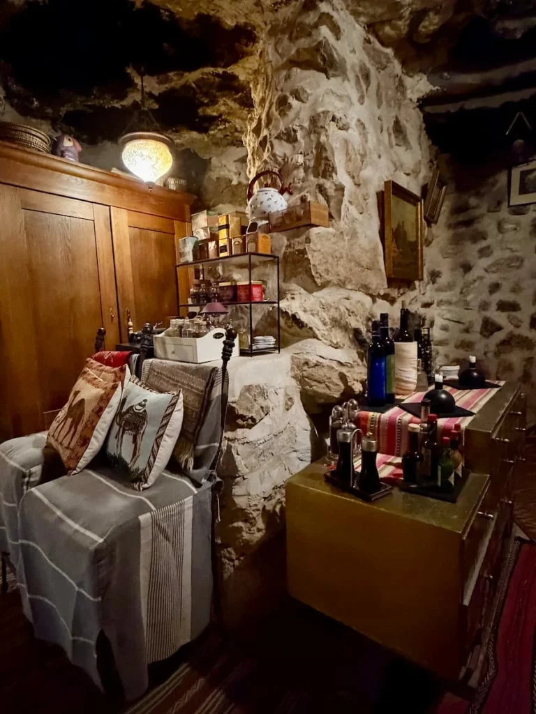 Wine cellar at L'Auberge de Tamezret, Tunisia. theer are bottles of vintage wine in teh cave-like wine cellar as well as cooking books and photos hanging on the cave walls.