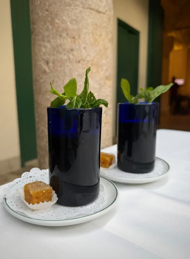 Mint tea at Fondouk el Attarine in blue cups garnished with real mint, accompanied by sweets, Tunis Medina, Tunisia