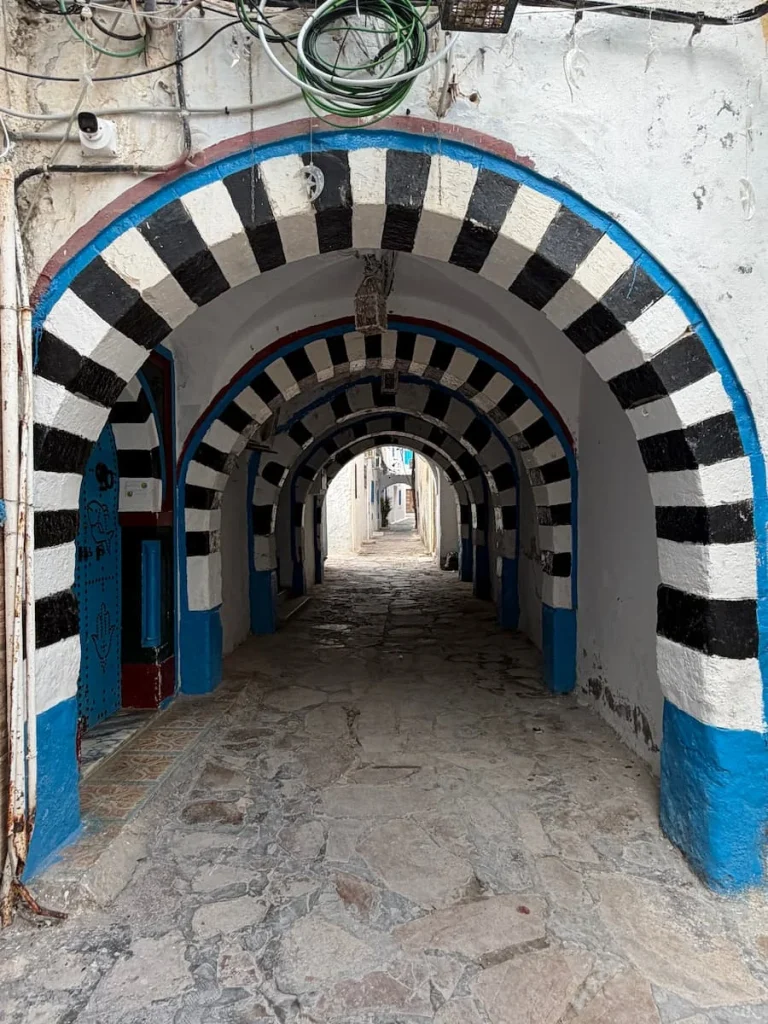 Black and white striped archways in Hammamet Medina with more shops in the far distance