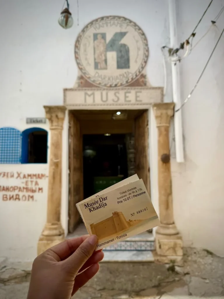 Dar Khadija Museum entrance with wooden door open adn Bejal holding the entrance ticket in front of the door.