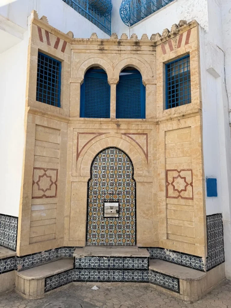 Intricate doorway in Kairouan Medina with blue top windows and a blue adn white tiled entranceway