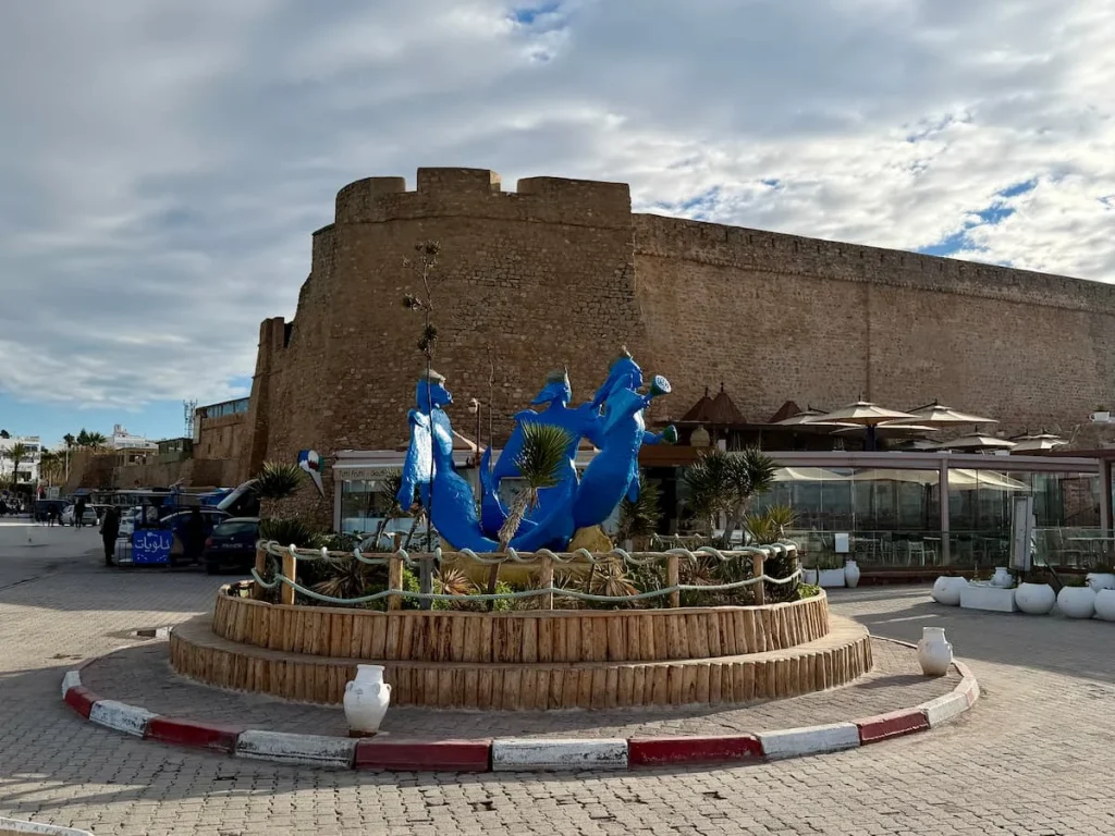 Blue Three mermaids statue, Hammamet. the statue is right in the middle of teh roundabout with the medina in the background