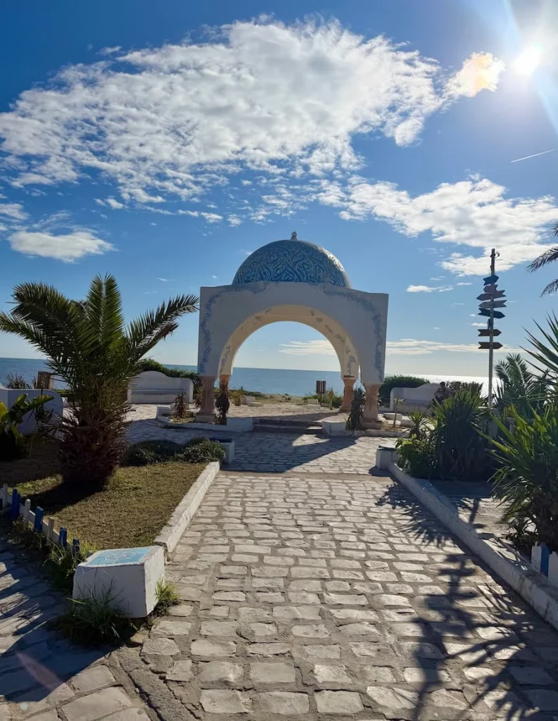 Walking path down promenade with sea in background, Hammamet. There are plants at either side lining the cobbled walkway