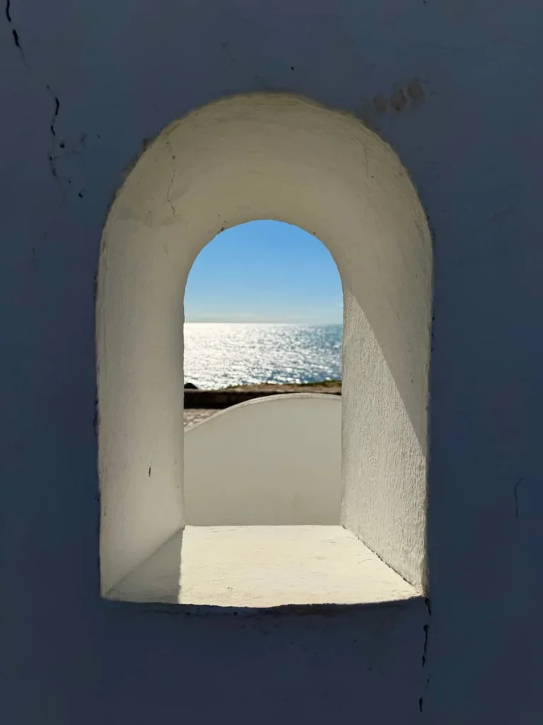 White washed window with sea view in Hammamet promenade area. In the distance is the shimmering sea and bright blue sky