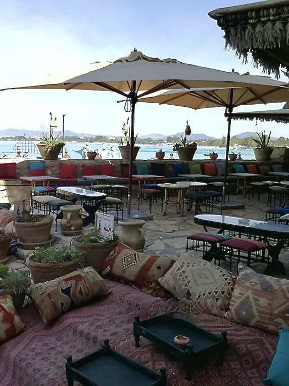 Sidi bou hdid Cafe outdoor seating area in Hammamet. There are colouful cushions, sun parasols and tables in the courtyard with sea views.